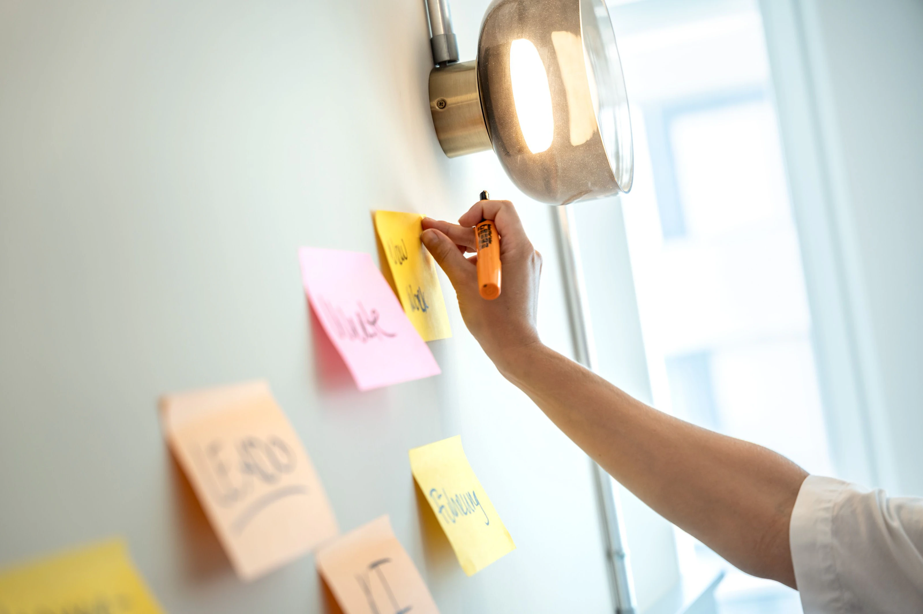 Eine Hand klebt Notizzettel an eine Wand