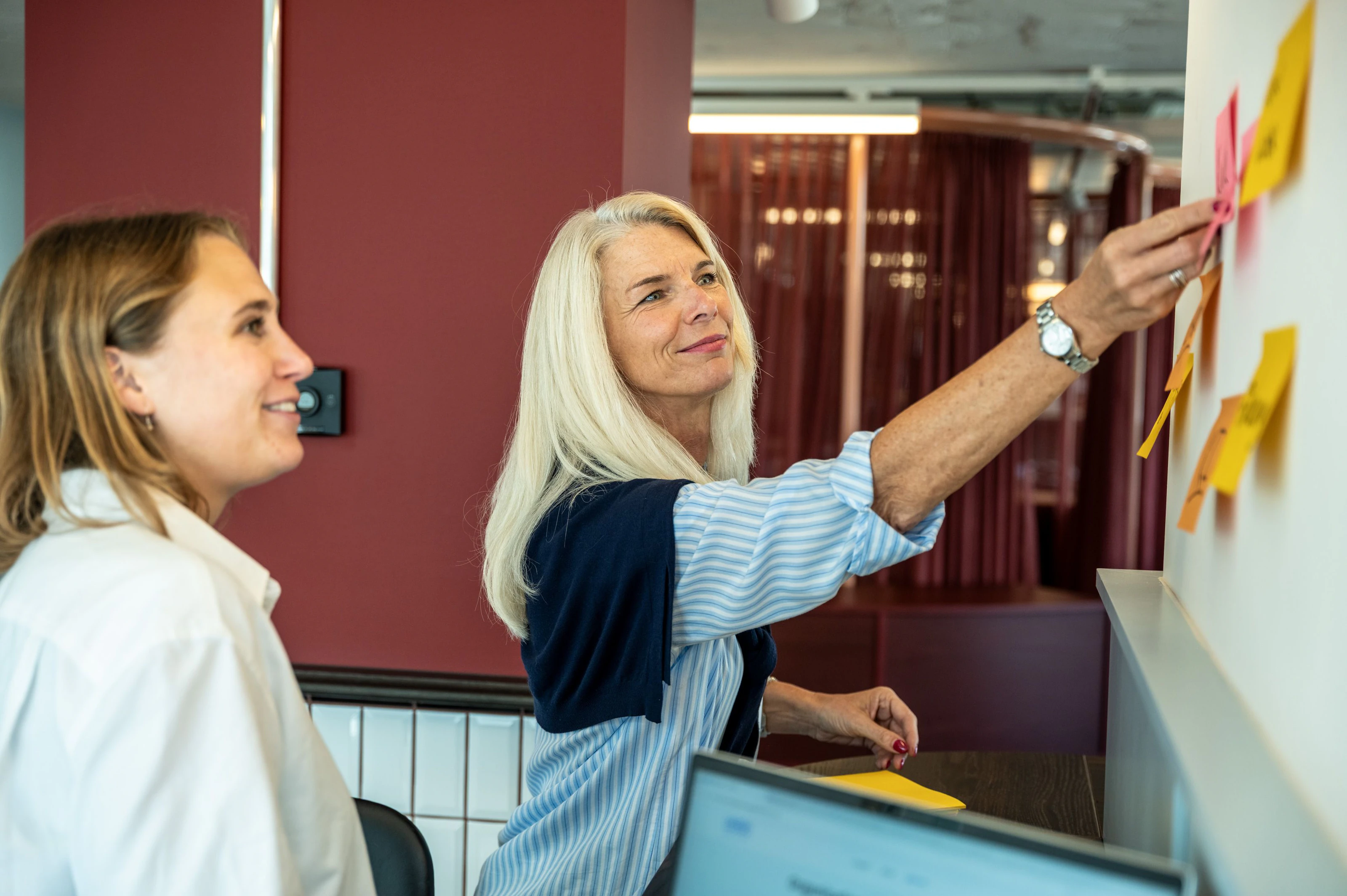 Kerstin Rufer und eine Kollegin ordnen Notizzettel an einer Wand