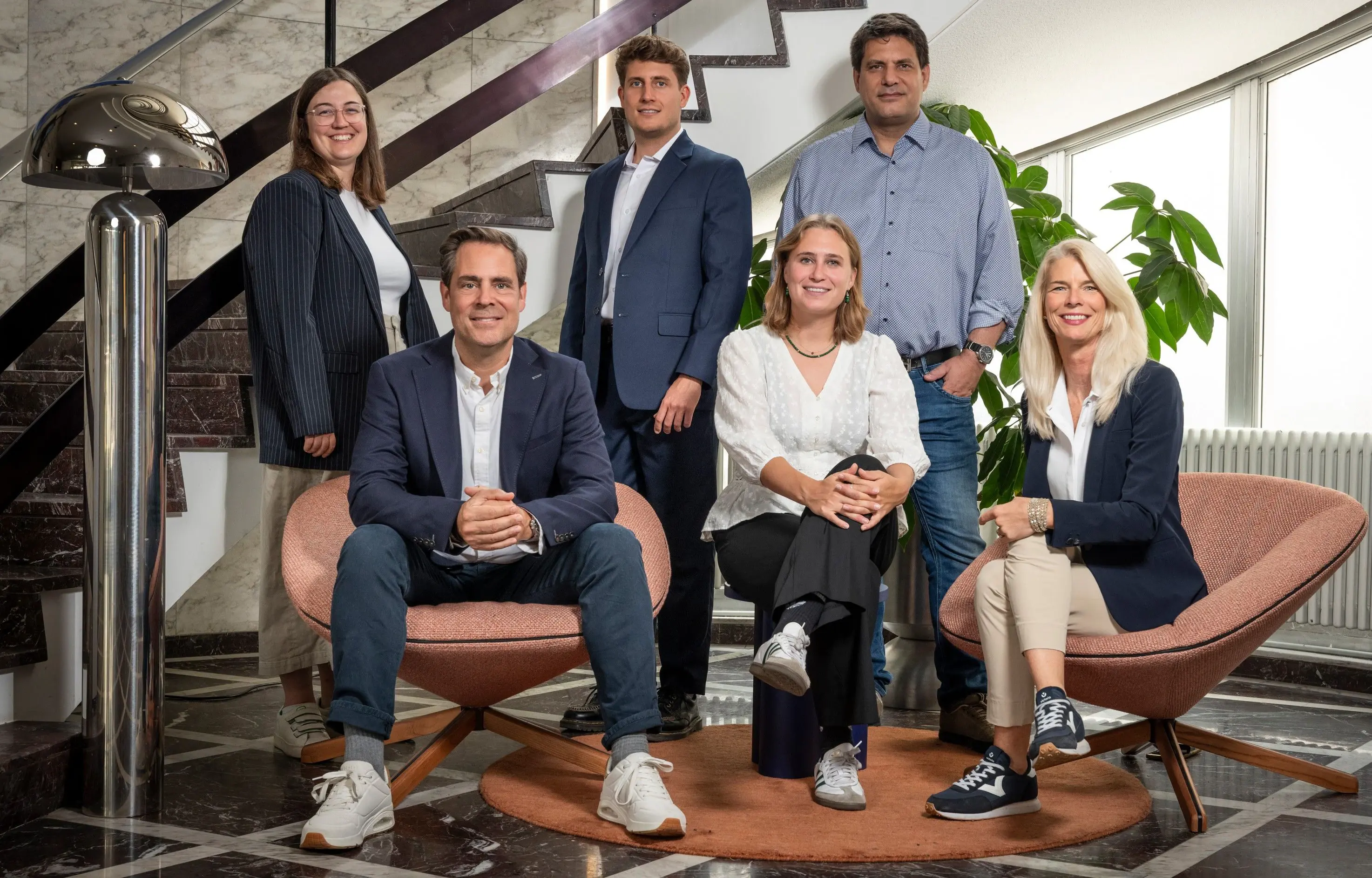 Das Team von Pfyffer Partner, sechs Personen in einem hellen Treppenhaus mit Lounge-Sesseln